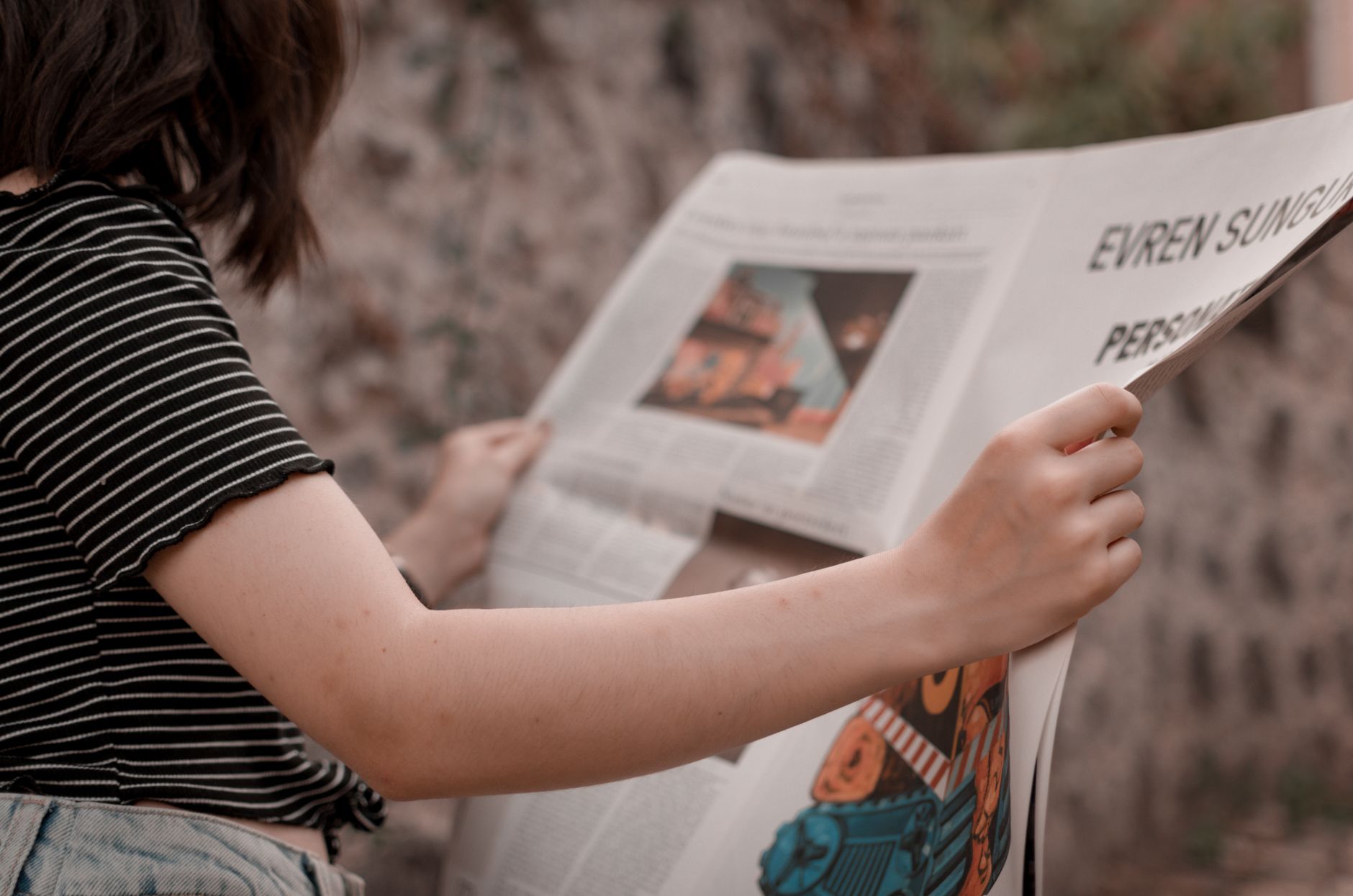 A woman holding a newspaper while sitting outside, enjoying a leisurely read. — Is Tiranga Game App Addictive? Signs to Watch